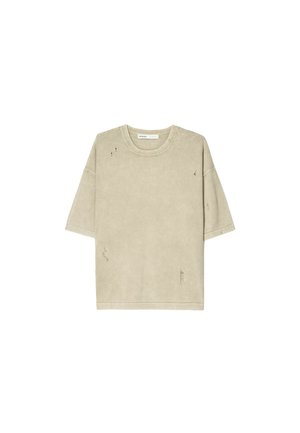 Béžové oversized tričko, krátke rukávy, okrúhly výstrih, má opotrebované detaily a trhané akcenty, vyrobené z mäkkej látky.