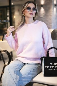 Helle rosa, übergroße Strickjacke mit geripptem Kragen und Bündchen. Kombiniert mit hellblauen Jeans und einer schwarzen Stofftasche.