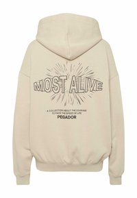 Beež kapuutsiga dressipluus, millel on nööriga kapuuts. Tagaküljel on päikesekiirtega "MOST ALIVE" graafiline kujundus ja selle all tekst. Pehme tekstuur.