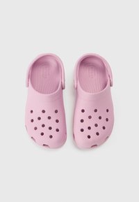 Rozā gumijas kluči ar caurumu dizainu, tostarp aizmugures siksnu drošai pielāgošanai un teksturētām zolēm ērtībai.