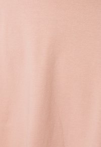 Ljusrosa tyg med en slät textur och subtil rippelstruktur. Materialet verkar mjukt och lätt.