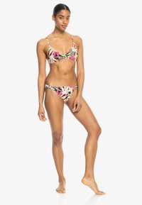 Bikini med blommönster i mörkt tyg. Bralette med tunna band och matchande låga bottnar med livfulla rosa, gröna och vita blommor.