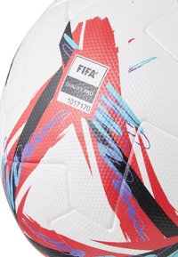 FIFA Quality Pro futbols, kas aprīkots ar teksturētu balto virsmu ar sarkaniem, melniem un ziliem rakstiem un vairākām heksagonālām paneļām.