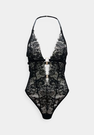 Musta pitsinen bodysuit, jossa on syvä V-aukko, säädettävät hihnat ja kullansävyinen yksityiskohta edessä. Läpinäkyvä kangas kukkakuviolla.