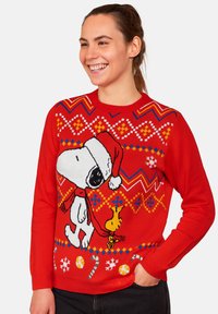 Maglione lavorato a maglia rosso con un ampio motivo di Snoopy che indossa un cappello di Babbo Natale, con pattern colorati e disegni di bastoncini di zucchero lungo l'orlo.