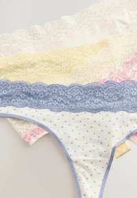 Lace-trimmed slips in pastelkleuren: wit, geel, roze en blauw met stippen, met zacht materiaal en golvende randen.