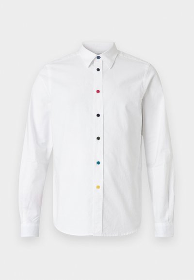 Camicia bianca a maniche lunghe con colletto abbottonato, caratterizzata da bottoni multicolori in rosso, blu, nero, verde e giallo lungo la parte anteriore.