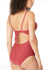 Frambooskleurige éénpiece badpak met spaghettibandjes, een open rugontwerp en een strikaccent op de taille. Gladde, rekbare stof.
