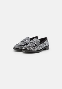 Mocassins noirs ornés de strass en argent, avec une surface texturée, un talon plat et un design à bout rond.