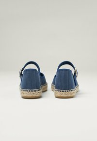 Espadrilles azul marino con parte superior de tela suave, tacón redondeado y suela de yute trenzado. Presentan una correa trasera con detalle de hebilla metálica.