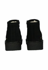 Botines de ante negros con una suela texturizada negra, que cuentan con un forro suave, cierre de cremallera y un diseño minimalista.