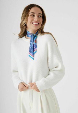 Witte, fluffy trui met een ronde hals, gecombineerd met een blauwe zijden sjaal met patronen en dierenprints. Zachte textuur en ontspannen pasvorm.