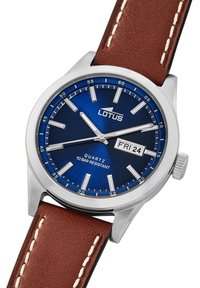 Reloj de cuarzo con esfera azul, caja de acero inoxidable plateado, correa de cuero marrón y display de fecha para el día y el mes. Resistente al agua hasta 10 bares.