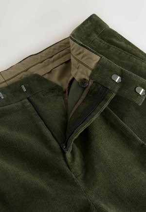 Tmavě zelené kordové kalhoty se hladkým podšívkou. Obsahují zip, zapínání na knoflík a kovové detaily. Zobrazeno texturované materiál.