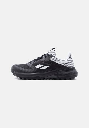 Pantof sportiv Reebok alb-negru cu talpă texturată și guler de material cu model, văzut din partea exterioară pe un fundal simplu.