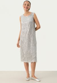 Silbernes ärmelloses Kleid mit vertikalen Fransen, knielang, glatte Textur, kombiniert mit silbernen flachen Schuhen. Einfaches, elegantes Design.