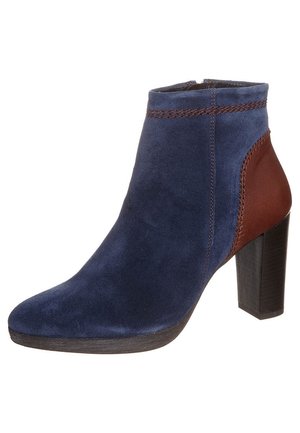 Bottine en daim bleu marine avec talon en cuir marron, talon carré, détail de bordure tressée et fermeture éclair latérale.