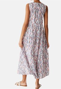 Robe maxi sans manches en tissu léger avec un motif en zigzag coloré. Le dos présente des détails froncés et une coupe décontractée.