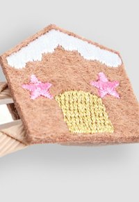 Ruske felt hiuspanta, joka on muotoiltu taloksi. Sen katto on valkoinen, siinä on vaaleanpunaisia tähtiä ja kullattu ovi, jossa on tekstuurista brodeerausta.