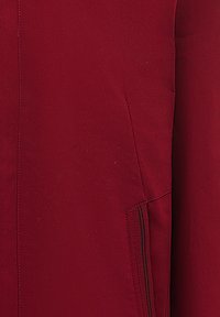 Giacca bordeaux con tessuto liscio, design aderente e una tasca nascosta con cuciture nere per un tocco di dettaglio.