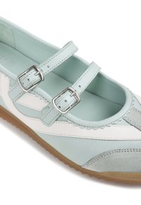 Chaussure plate bleu clair et blanche avec deux brides réglables à boucle argentée et une semelle marron texturée.