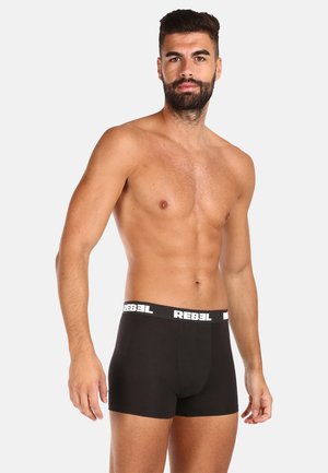 Zwarte boxershorts van rekbare stof, met een witte merkband. Het ontwerp is aangesloten en heeft een gladde textuur.