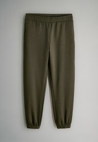 Pantaloni jogger verde oliva scuro con cintura e polsini elasticizzati, esposti su uno sfondo grigio chiaro.