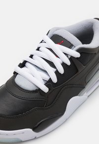 Scarpa sportiva nera con tomaia in pelle e rete, lacci bianchi e dettagli grigi. Presenta un'unità air visibile nella suola e dettagli testurizzati.