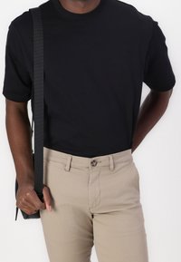 Black short-sleeve t-shirt paired with beige trousers. T-shirt features a round neckline, trousers have a button closure, and a smooth texture.