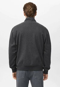 Giacca zip-up grigio scuro con colletto alto, polsini rigati e orlo; realizzata in materiale morbido con una finitura testurizzata.