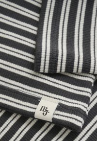 Textil med ett mörkblått och vitt randigt mönster, slät textur, med en synlig vit etikett präglad med "IBJ."