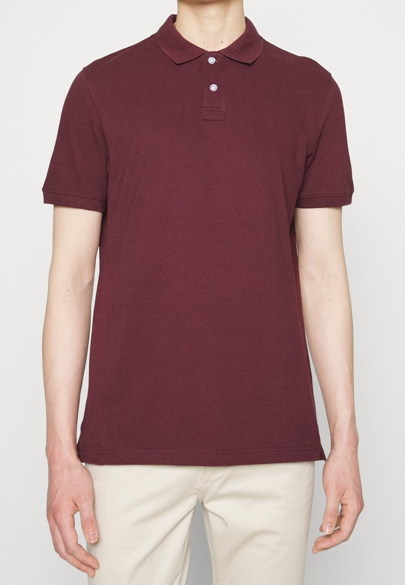Polo bourgogne à manches courtes, avec un plastron à deux boutons et une texture en coton doux. Tissu lisse et design de col classique.
