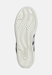 Gumeni đonovi za tenisice u bijeloj boji s cik-cak uzorkom, s ušivenim logotipom i tamnim prugama sa strane za bolje prianjanje i izdržljivost.