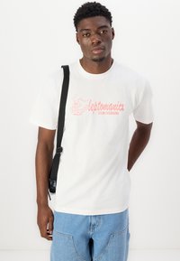 White cotton t-shirt featuring a pink graphic print with "leptomanicx CLUB CULINAIRE" text and a cartoon design. Casual fit and short sleeves.