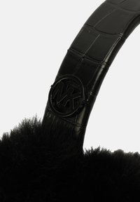 Sandale à bordure en fourrure noire avec une sangle en cuir noir laqué texturé comportant un accent circulaire du logo MK.