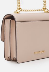 Borsa a mano in pelle beige con tracolla a catena dorata, presenta due scomparti e il logo del marchio in rilievo dorato sulla parte anteriore.