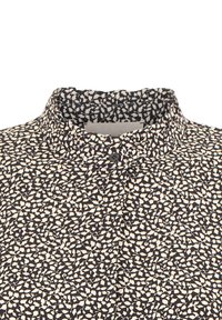 Czarna i ecru bluzka w kwiatowy wzór z wysokim kołnierzem. Tkanina jest lekka i ma gładką powierzchnię.