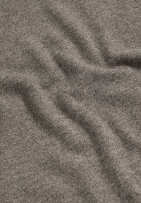 Tissu gris doux avec une texture fine en tricot et des plis délicats créant des ombres et des reflets subtils.