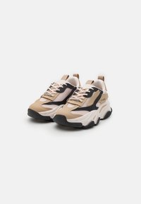 Beige and black sneakers with mesh panels, textured rubber sole, and contrast stitching. Features lace-up design and rear pull tab.