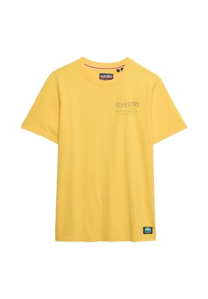 T-shirt gialla a maniche corte con scollo tondo, con piccolo logo "Superdry Outfitters Co." sul petto e toppa rettangolare vicino all'orlo inferiore.