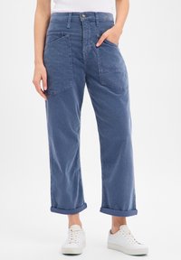 Pantalon cargo bleu clair à jambes larges avec revers roulés, poches avant et fermeture par bouton. Confectionné en tissu de coton doux et texturé.