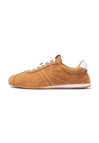 Brown suede sneaker with white lace-ups, contrasting white stitching, and a white heel accent. Low-top design with a flexible sole.