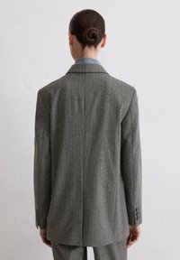 Grijze gestreepte blazer met een gestructureerde silhouet, afgesneden revers en vierknopenmanchetten. Gladde stof met een lichte glans.