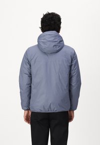 Giacca con cappuccio di un blu chiaro, dal texture morbida, con polsini e orlo elasticizzati, caratterizzata da un design semplice senza marchi o decorazioni visibili.