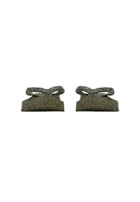 Groene teenslippers met een getextureerde band en geweven zool. De band heeft een subtiele glans, waardoor het tactiele ontwerp wordt versterkt.
