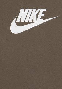 T-shirt en coton marron avec un grand logo Nike blanc sur la poitrine, doté d'une texture lisse et d'un col rond.