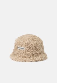 Beige bucket hat i texturerad, lockig tyg, med en etikett som har "lollys laundry" på sidan. Mjuk och avslappnad design.
