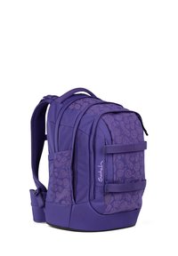 Purple Satch backpack with multiple zippered compartments, patterned with subtle smiley faces, and adjustable padded shoulder straps.