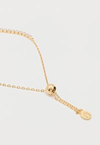 Χρυσό κολιέ με αλυσίδα και κούμπωμα με μετακινούμενη χάντρα, με τμήμα διακοσμημένο με στρας και μικρό εξαγωνικό μενταγιόν στο τέλος.