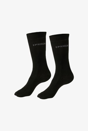 Par de calcetines negros con canalé y texto gris "CPHHGH" cerca del puño superior, mostrados sobre un fondo blanco.